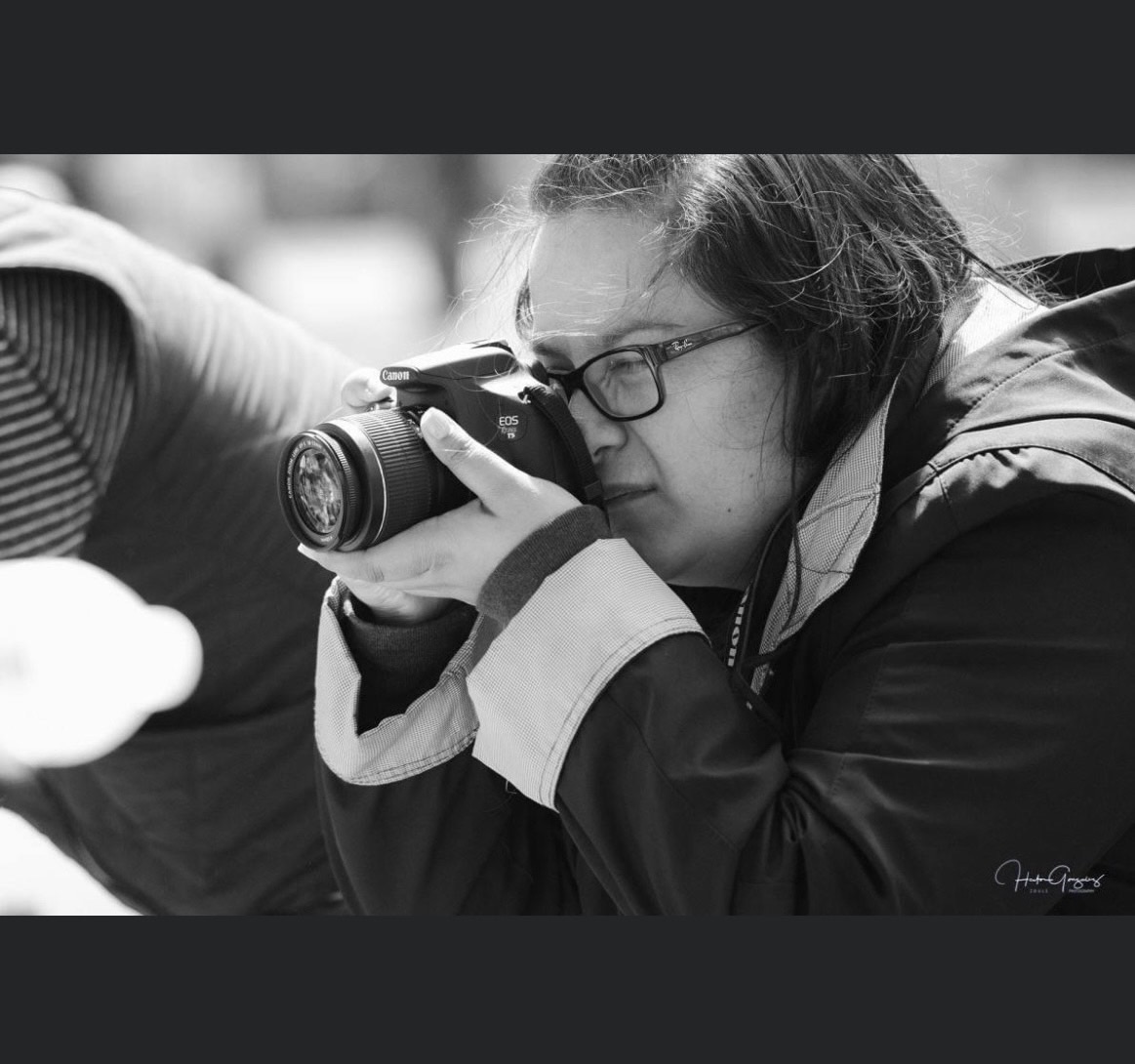 black and white photo of owner in black jacket taking photos at an event